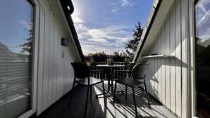 Parvekkeella on pöytä ja tuolit, ruukkuistutettu kasvi ja sieltä avautuu näkymä taivaalle.