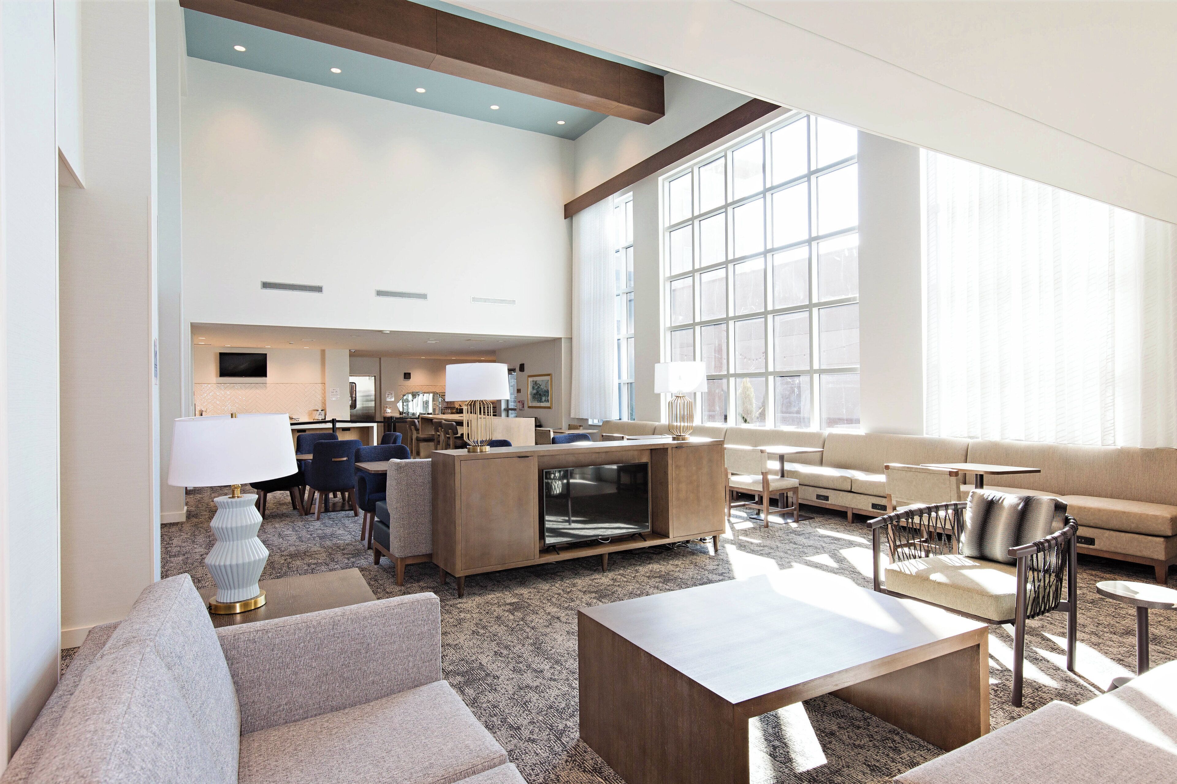 A spacious hotel lobby with a large seating area, a television, and a reception desk.