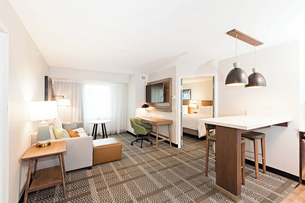 A hotel room with a sofa, desk, and two pendant lights.