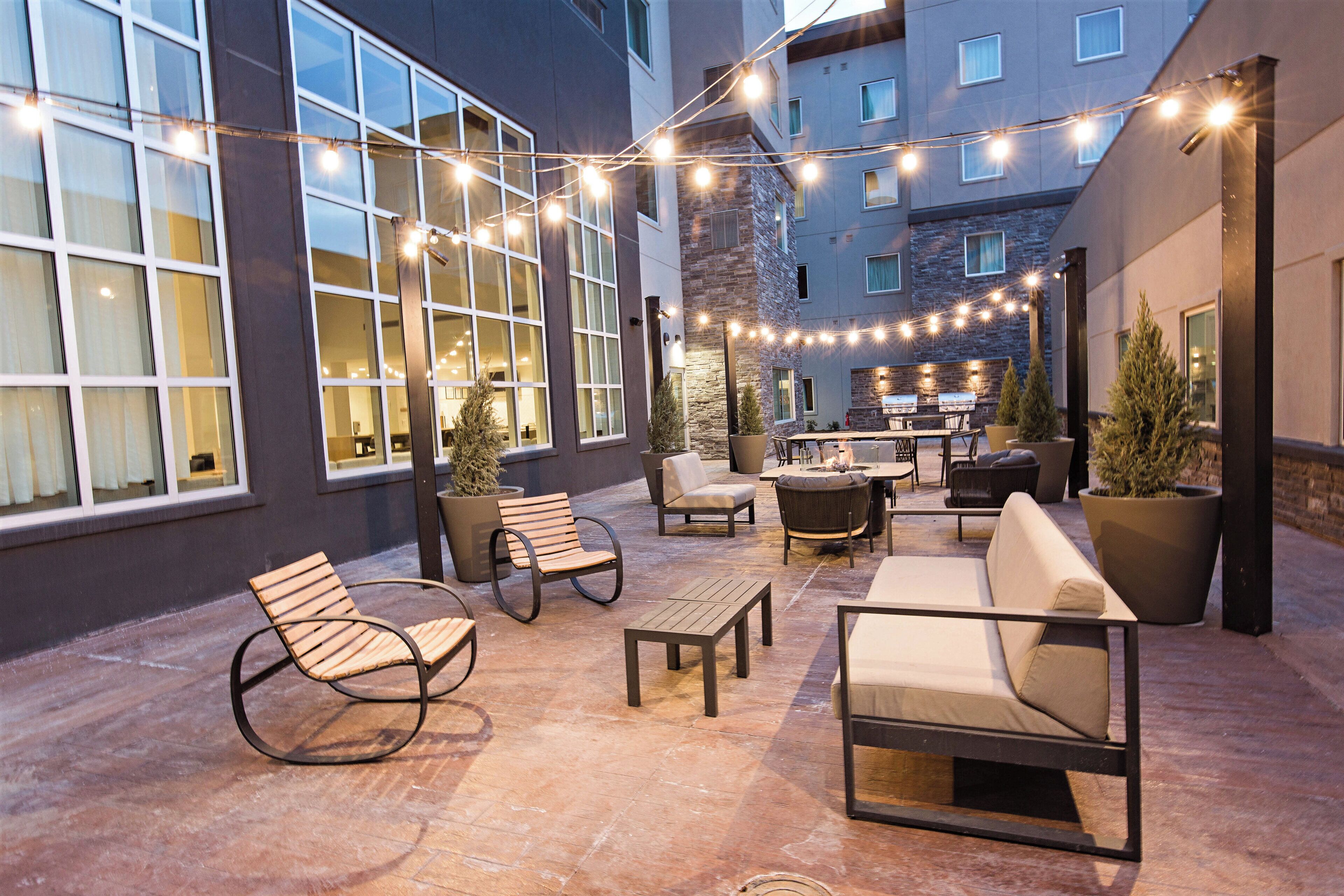 Un espace extérieur aménagé avec une terrasse, des sièges, des guirlandes lumineuses et un foyer.
