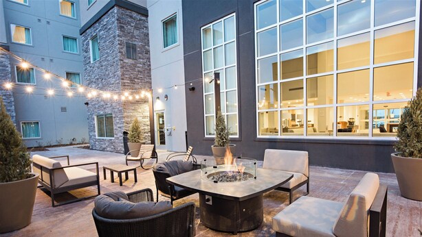 An outdoor patio with a fire pit, seating, and string lights.