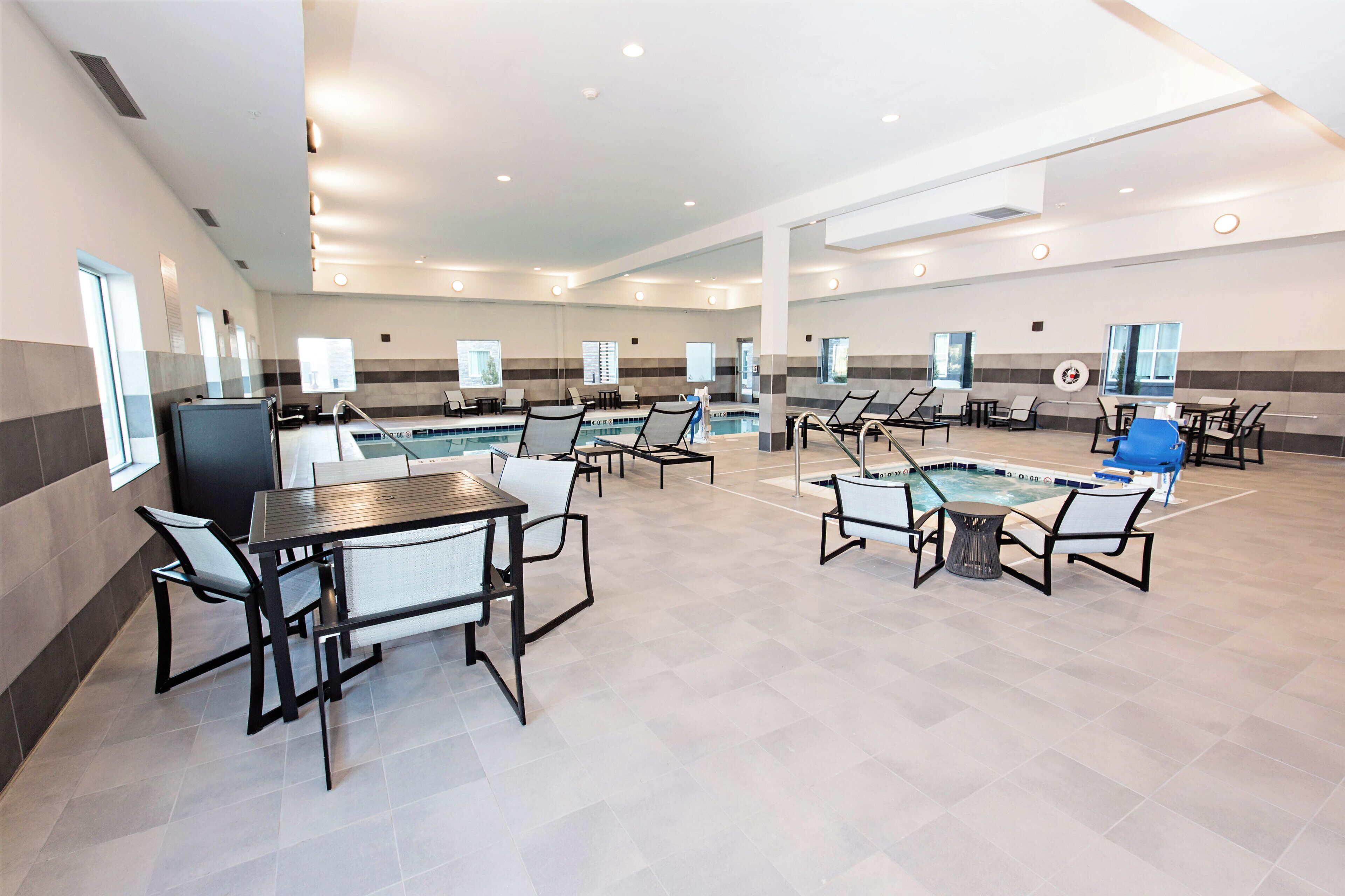 A spacious indoor area with multiple seating arrangements, a pool, and a clear view of the sky through the windows.