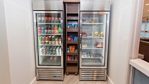 A row of three refrigerated display cases in a commercial setting, containing a variety of beverages and snacks. - Staybridge Suites Denver North - Thornton by IHG (Thornton)