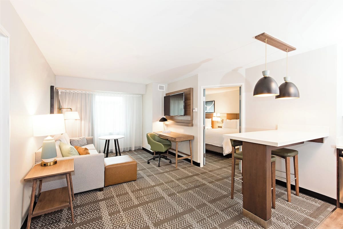 A hotel room with a sofa, desk, and two pendant lights.