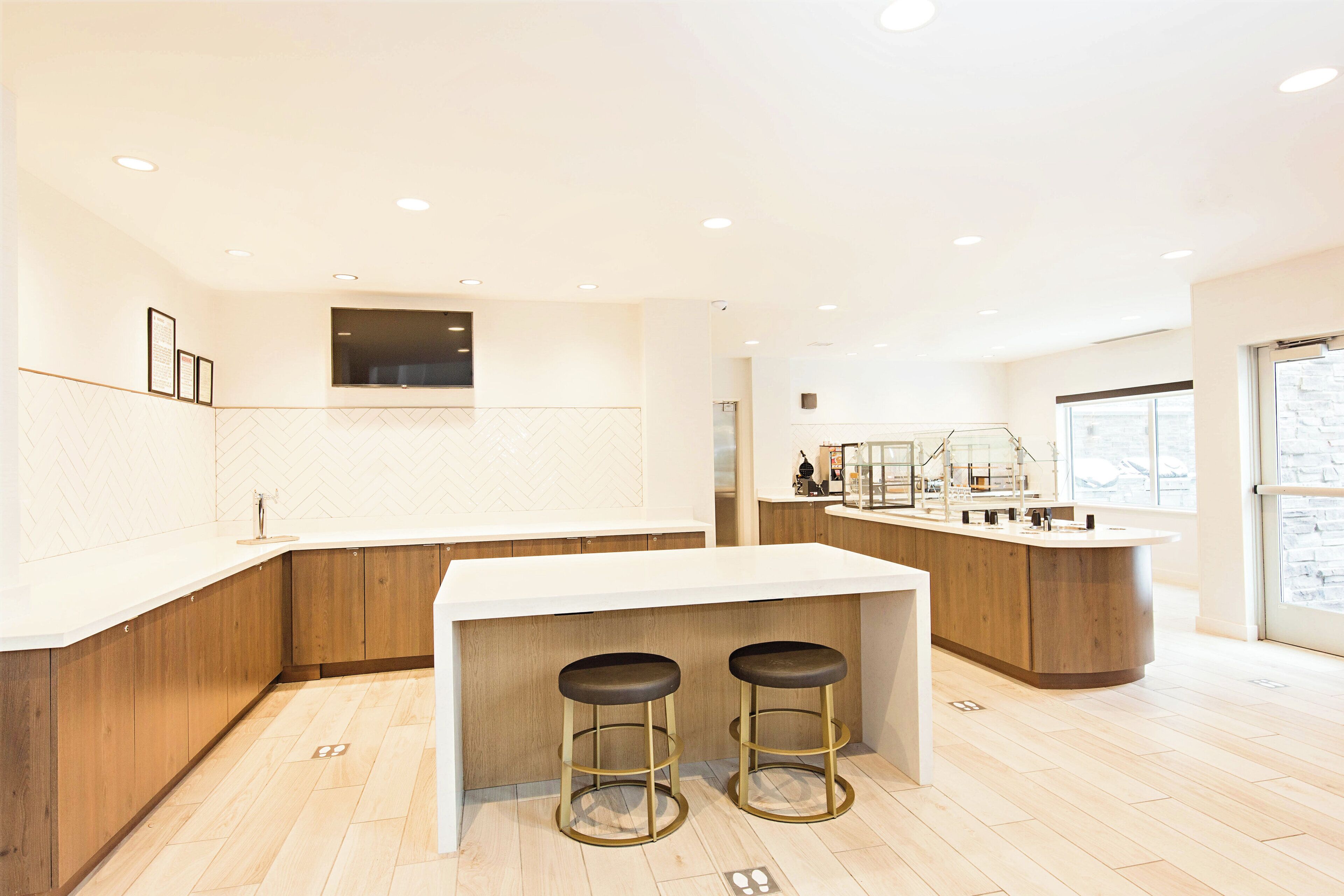 Une cuisine moderne dotée d’un îlot central, de meubles en bois et de deux tabourets de bar.