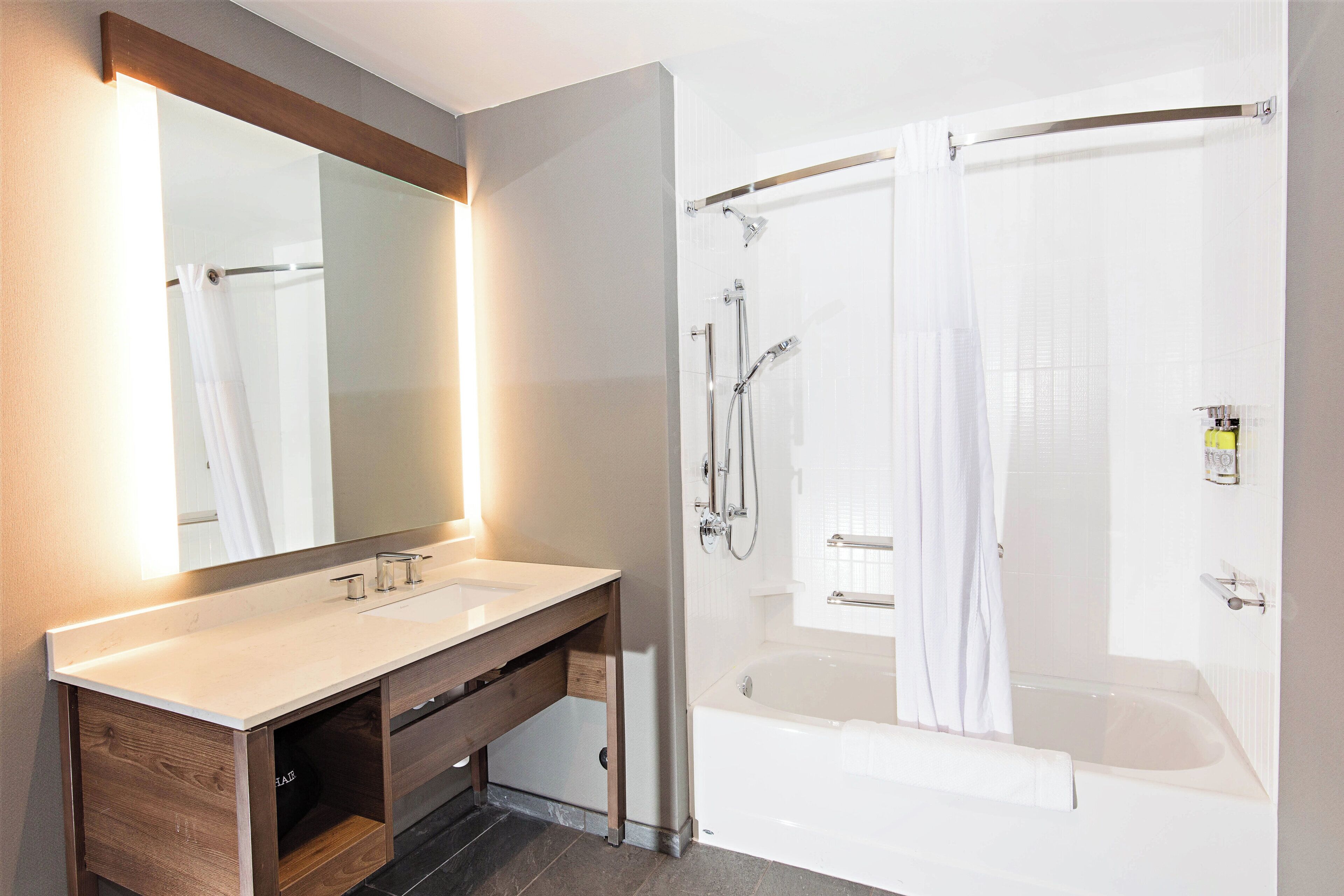 Une salle de bain moderne avec une douche à parois de verre, un meuble-lavabo en bois et un grand miroir.