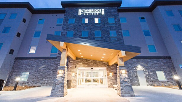 A Staybridge Suites hotel with a stone facade, multiple windows, and a covered entrance. - Staybridge Suites Denver North - Thornton by IHG (Thornton)