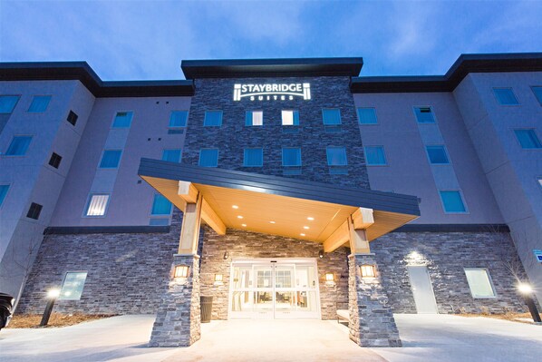 A Staybridge Suites hotel with a stone facade, multiple windows, and a covered entrance. - Staybridge Suites Denver North - Thornton by IHG (Thornton)