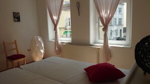 A room with a bed, a chair, a radiator, and a window with curtains. - On the edge of the historic old town, vacation apartment right in the center - 01 Family (Bautzen)