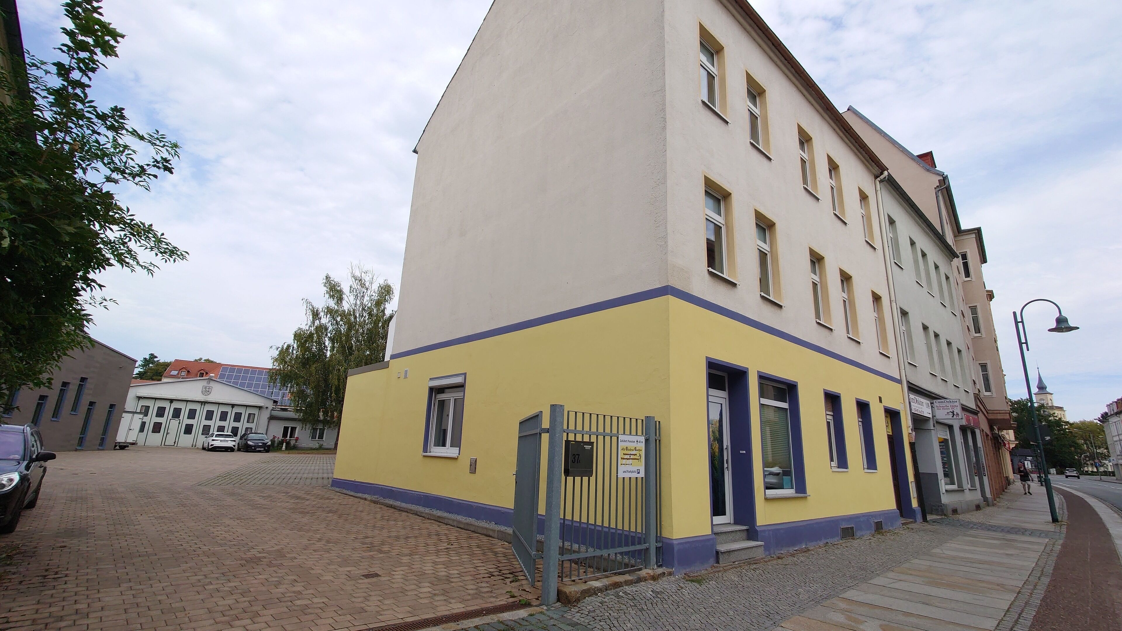 Ein gelbes Gebäude mit vielen Fenstern und einem verschlossenen Eingang.