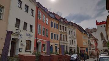 Een rij kleurrijke historische gebouwen, met een restaurant genaamd 'Der Griechische' aan de linkerkant.
