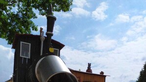 A playground with a metal slide, wooden climbing structures, and a red-roofed playhouse. - On the edge of the historic old town, vacation apartment right in the center - 01 Family (Bautzen)