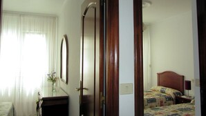 A hotel room with a bed, a bedside table, a mirror, and a window with curtains. - Apartment Seaview in O Pindo (O Pindo)