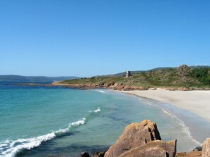 A coastal beach with clear waters, a sandy shore, and rocky outcrops. - Apartment Seaview in O Pindo (O Pindo)