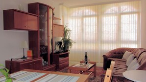 A living room with a sofa, a dining table with a placemat, a cabinet, and a window with blinds. - Apartment Seaview in O Pindo (O Pindo)