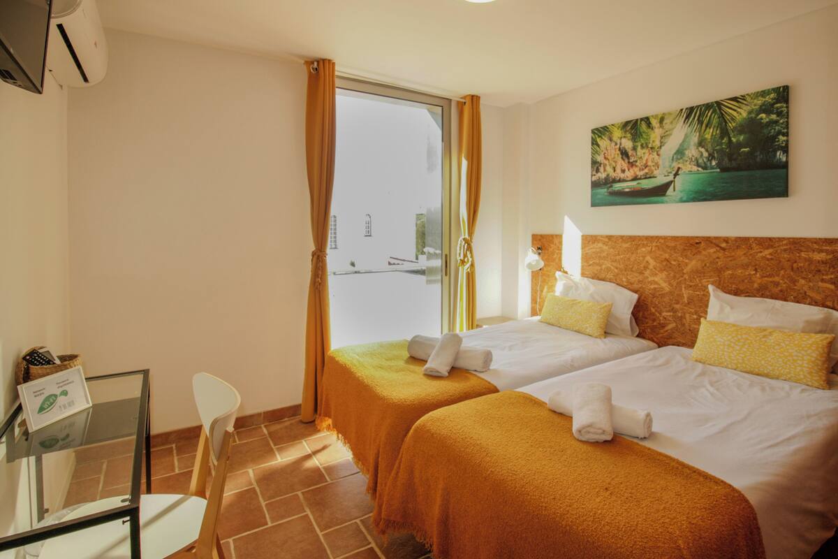 A hotel room with two beds, a desk, and a chair.