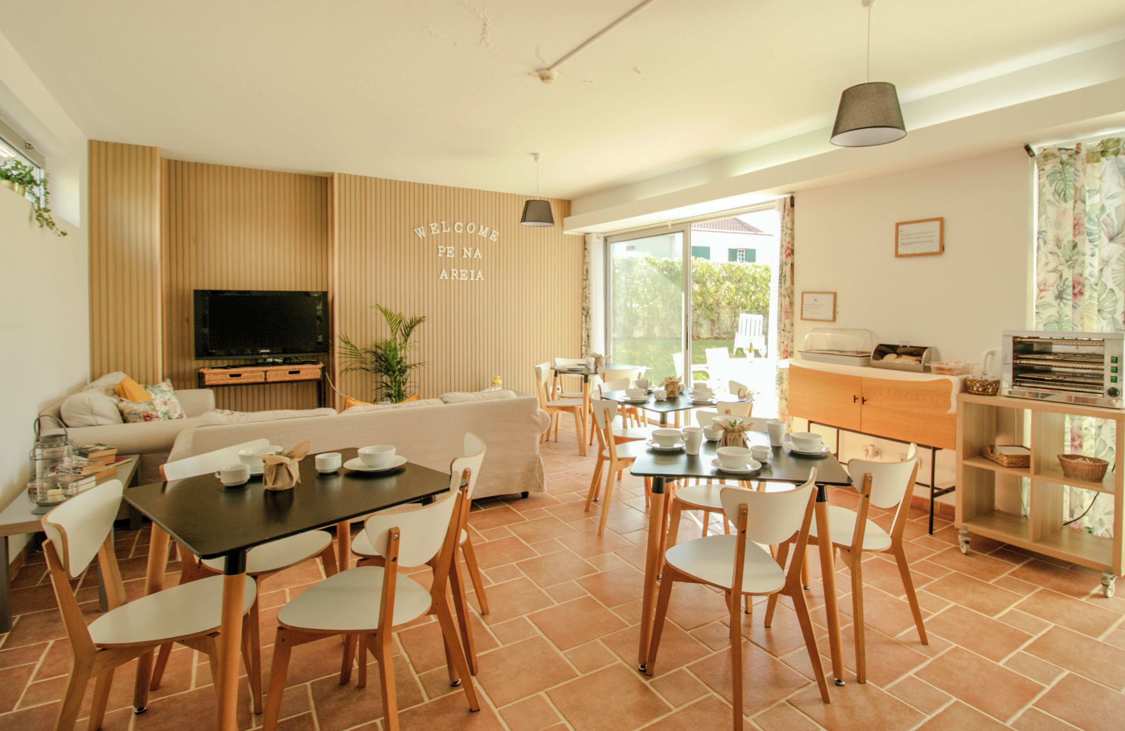 Una sala de estar moderna con un sofá, mesa de comedor, sillas, televisor y una zona de cocina con armarios y encimera.