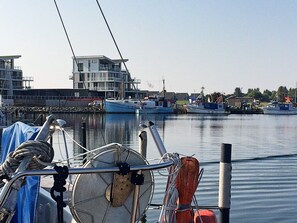 A marina with boats docked, a building with a balcony, and calm water.