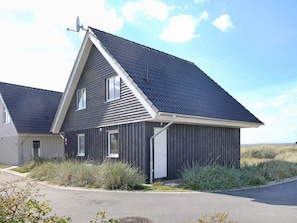 A single-story building with a gabled roof, a satellite dish, and a door.