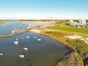 A marina with boats docked, a construction crane, and a building complex in the background. - Holiday Home in Wendtorf (Wendtorf)