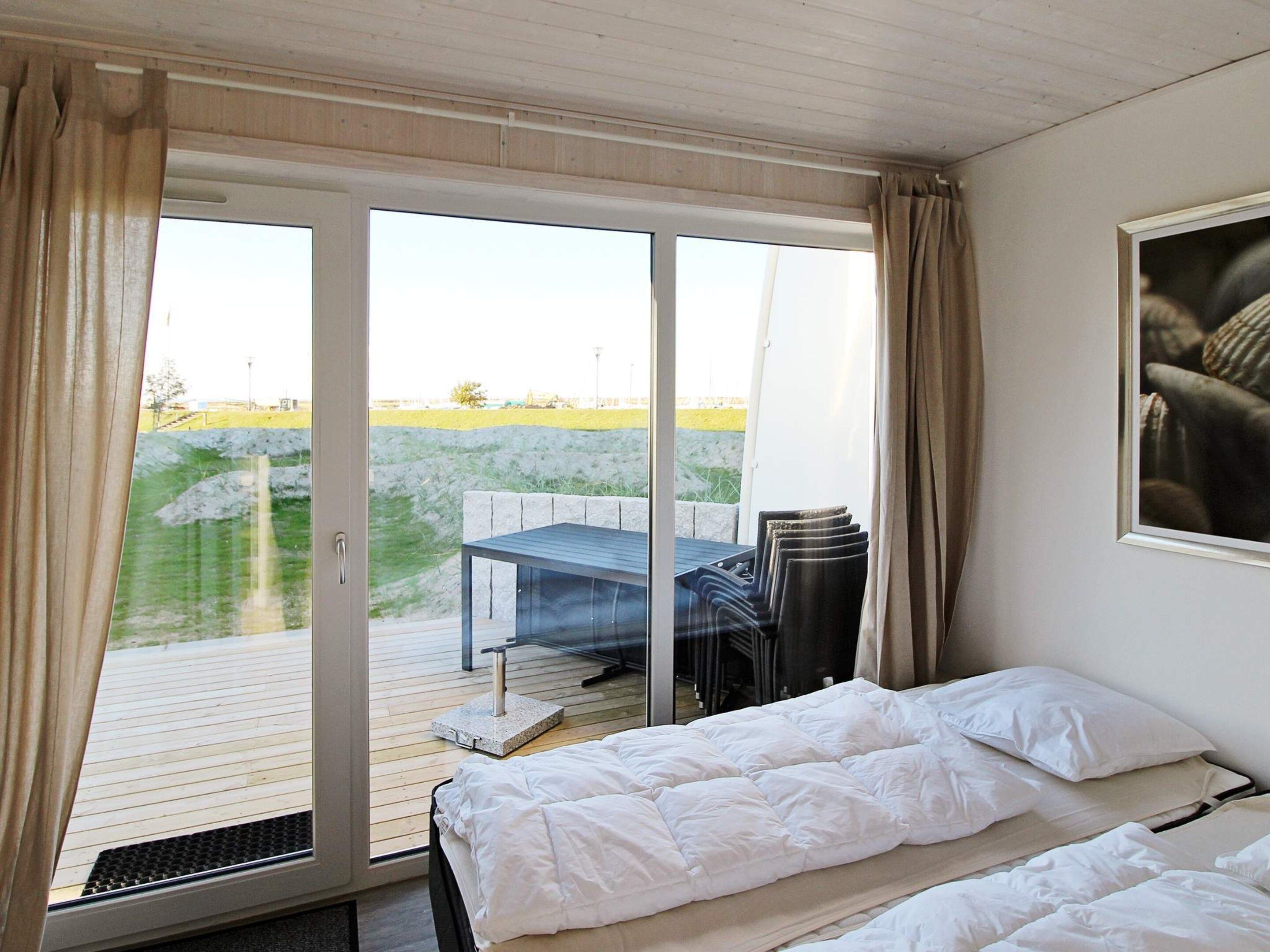 A bedroom with a bed, a table, and chairs outside a sliding glass door.