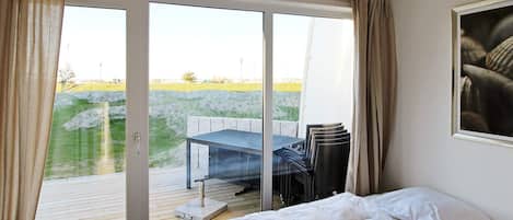 A bedroom with a bed, a table, and chairs outside a sliding glass door.