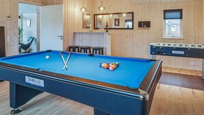 A pool table with a blue felt surface, a billiards table, wooden walls, and a mirror above the pool table. - Holiday Home in Kappeln (Kappeln)
