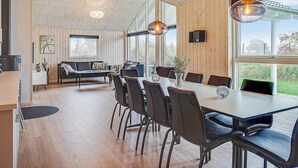 A modern dining area with a long table, chairs, and pendant lighting. - Holiday Home in Kappeln (Kappeln)