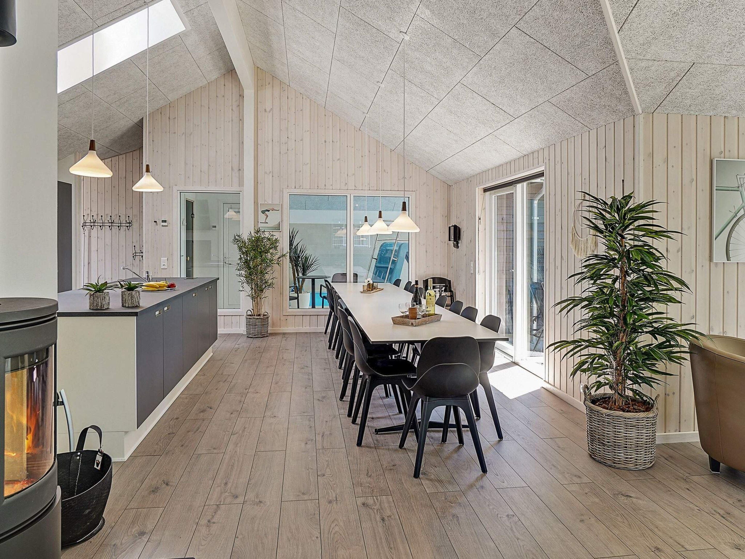 A spacious kitchen with a large island, wooden flooring, and a dining area with a long table and chairs.