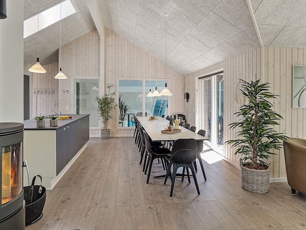 A spacious kitchen with a large island, wooden flooring, and a dining area with a long table and chairs. - Holiday Home in Kappeln (Kappeln)