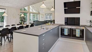 A modern kitchen with a large island, built-in appliances, and pendant lighting. - Holiday Home in Kappeln (Kappeln)