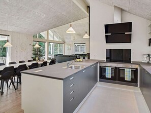 A modern kitchen with a large island, built-in appliances, and pendant lighting.