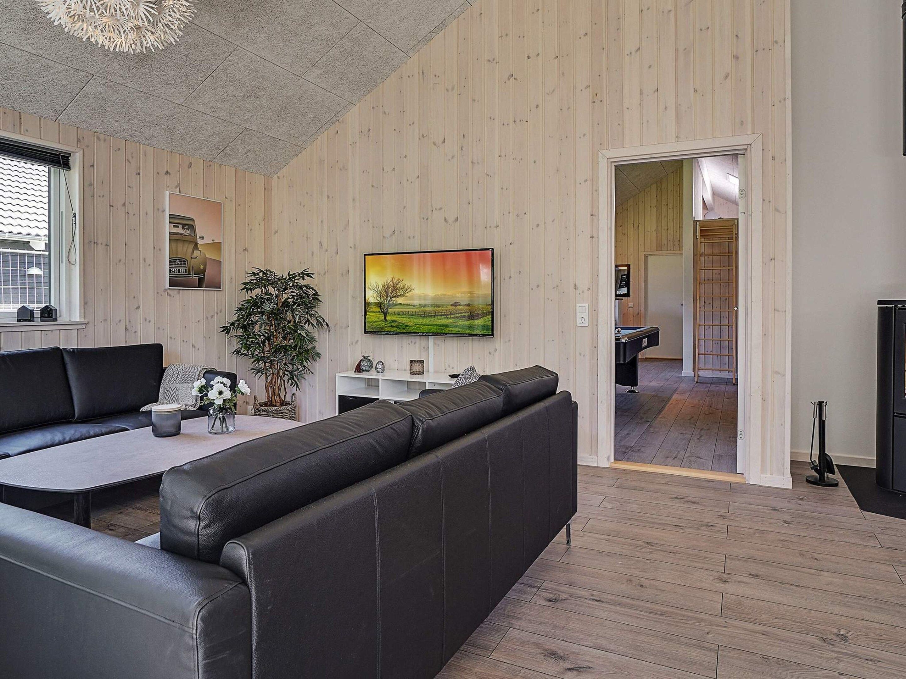 A modern living room with a sofa, TV, and a plant.