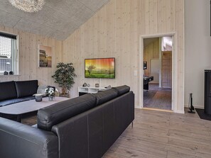 Una sala de estar moderna con un sofá, televisor y una planta.