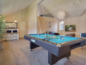 A pool table with balls, a bar area with stools, a television, and a wooden interior.