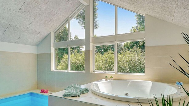 A modern bathroom with a bathtub, a shower, and a window overlooking greenery. - Holiday Home in Kappeln (Kappeln)