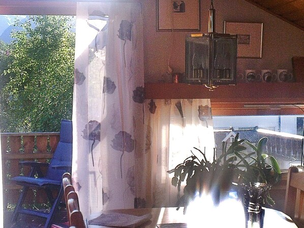 Una habitación con techo de madera, una silla, una mesa y una planta en maceta.