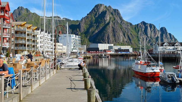 Un port de plaisance avec des bateaux, une jetée en bois et des bâtiments dotés de balcons.