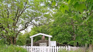 Un jardin agrémenté d’un kiosque blanc, d’un mur de pierre et d’une clôture en bois peinte en blanc.