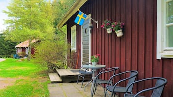 A wooden building with a flag, outdoor seating, and potted plants.