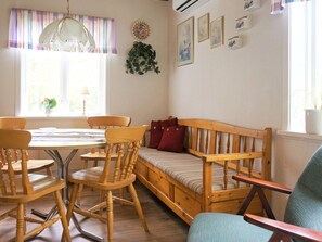 Une pièce chaleureuse avec un banc en bois, une table à manger avec des chaises et une fenêtre avec des rideaux.