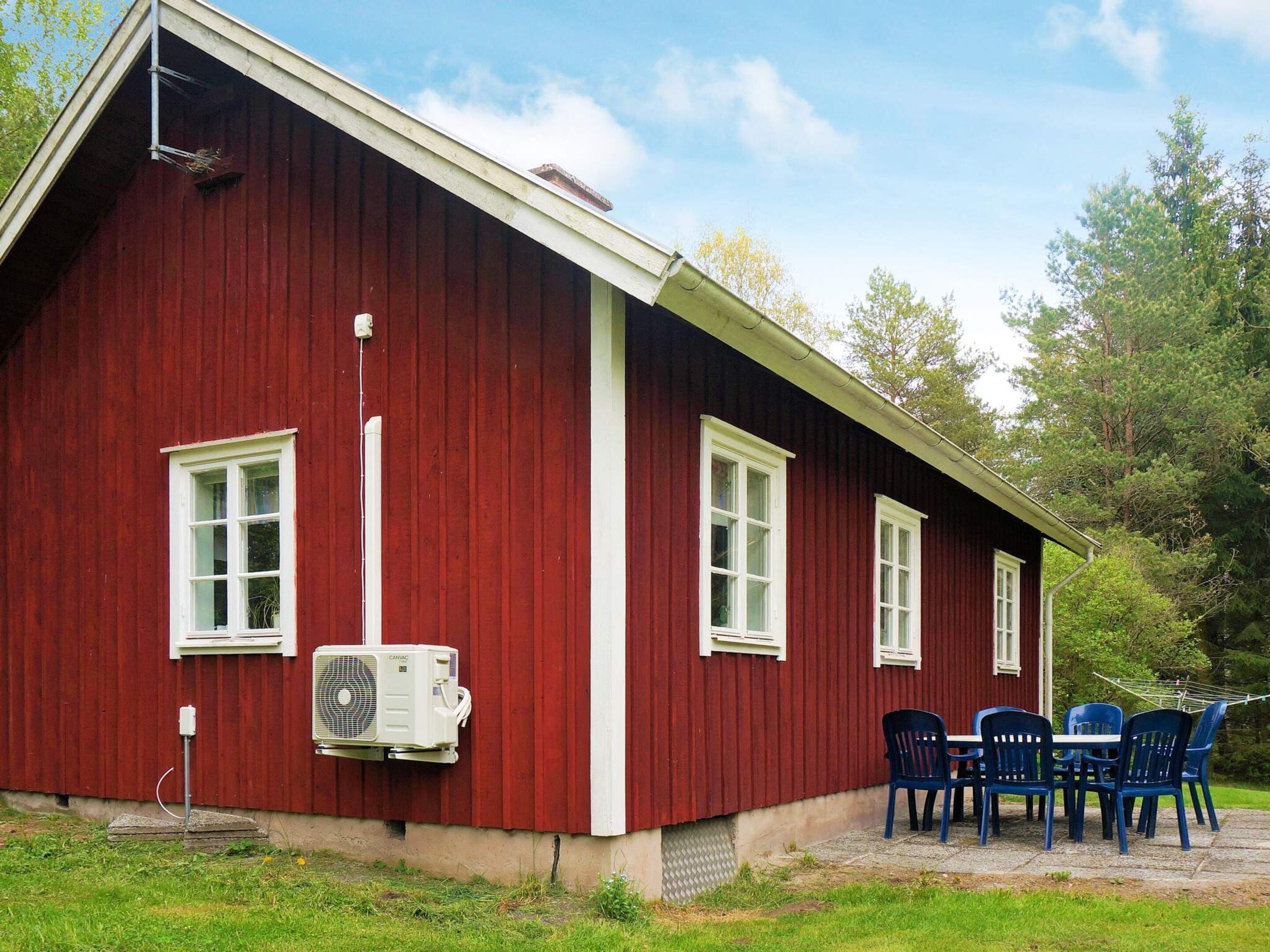 A red building with white trim, a window, and an air conditioning unit.