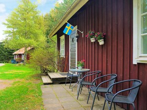 A wooden building with a flag, outdoor seating, and potted plants.