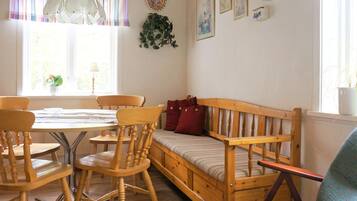 Une pièce chaleureuse avec un banc en bois, une table à manger avec des chaises et une fenêtre avec des rideaux.
