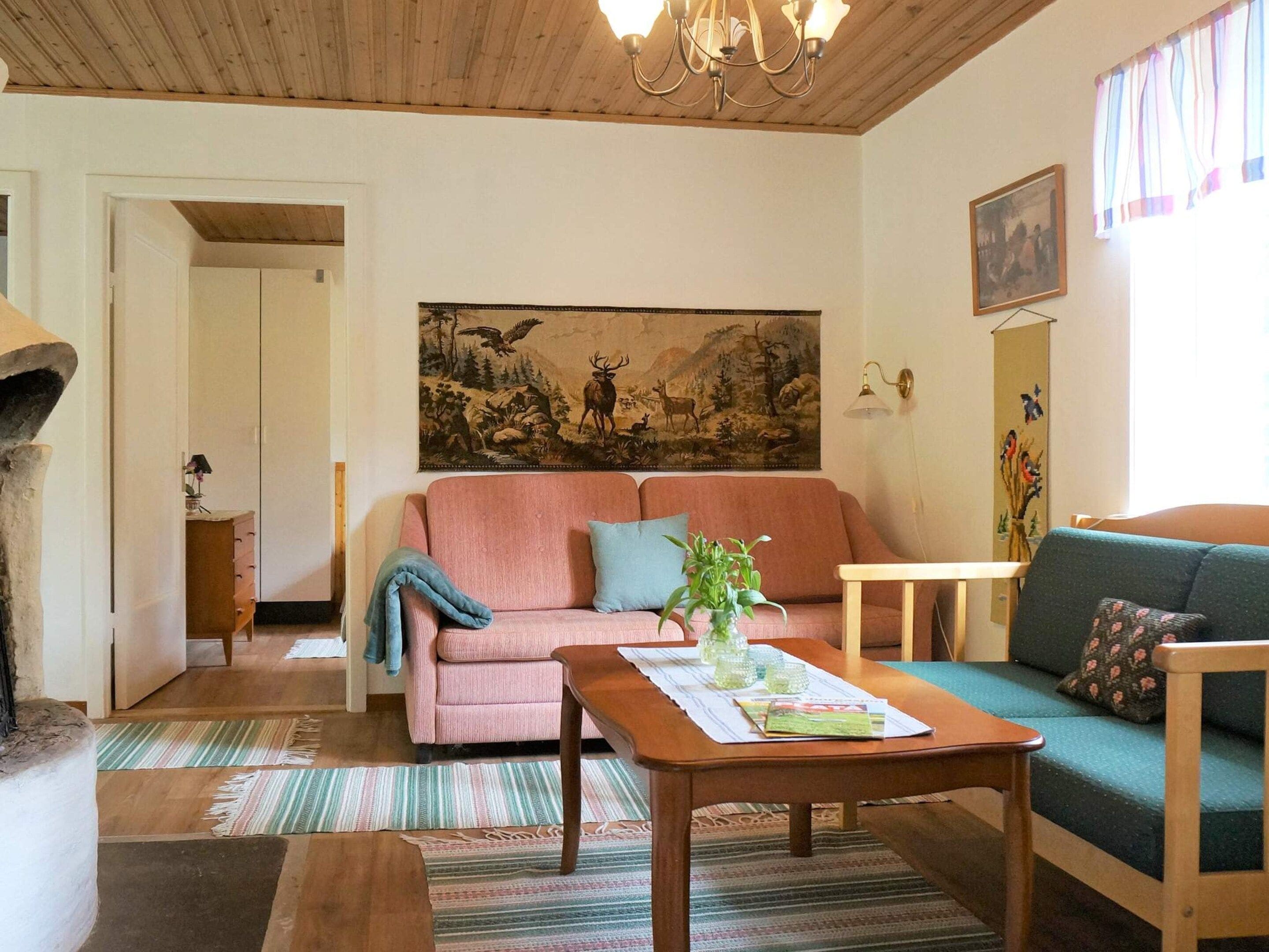 A living room with a pink sofa, a green sofa, a wooden coffee table, and a painting on the wall.