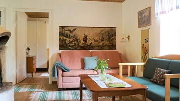 A living room with a pink sofa, a green sofa, a wooden coffee table, and a painting on the wall.