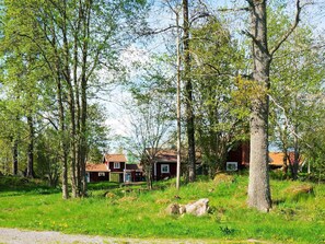 Un cadre rural, avec une maison entourée d’arbres et d’herbe.