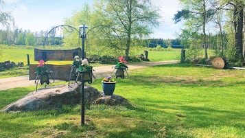 A bench with a metal frame and a wooden seat, positioned on a grassy area with a large rock nearby.