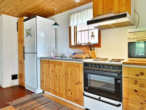 A compact kitchen with wooden cabinets, a built-in oven, a microwave, and a wooden ceiling. - 4 Person Holiday Home in Hallabro (Hallaröd)