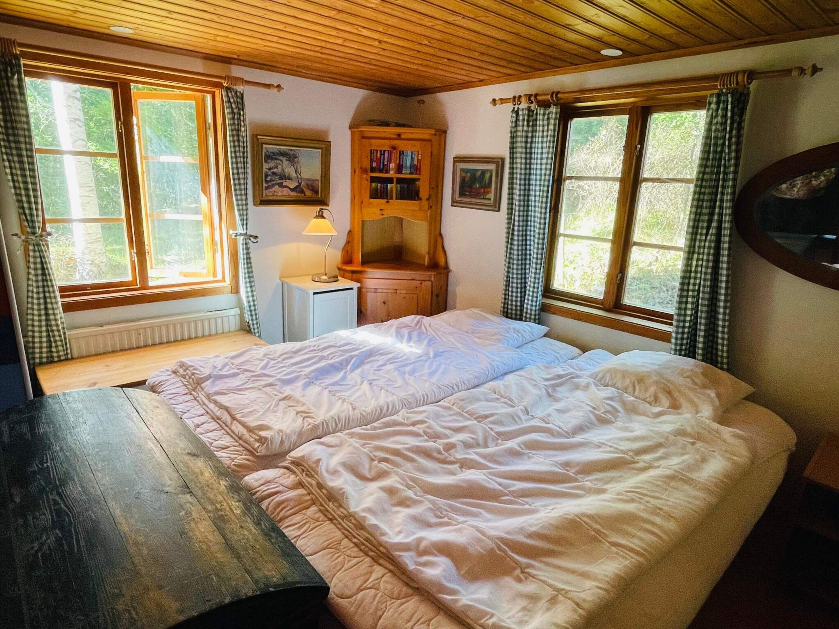 Un dormitorio con una cama doble, un escritorio de madera, una estantería y una ventana con cortinas.